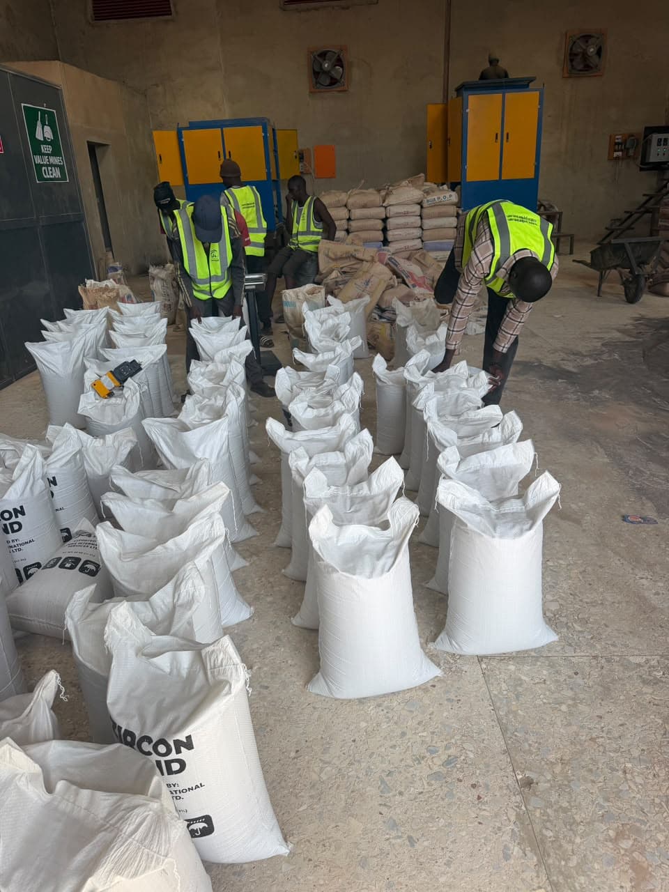 Workers in high-visibility vests weighing and filling bags